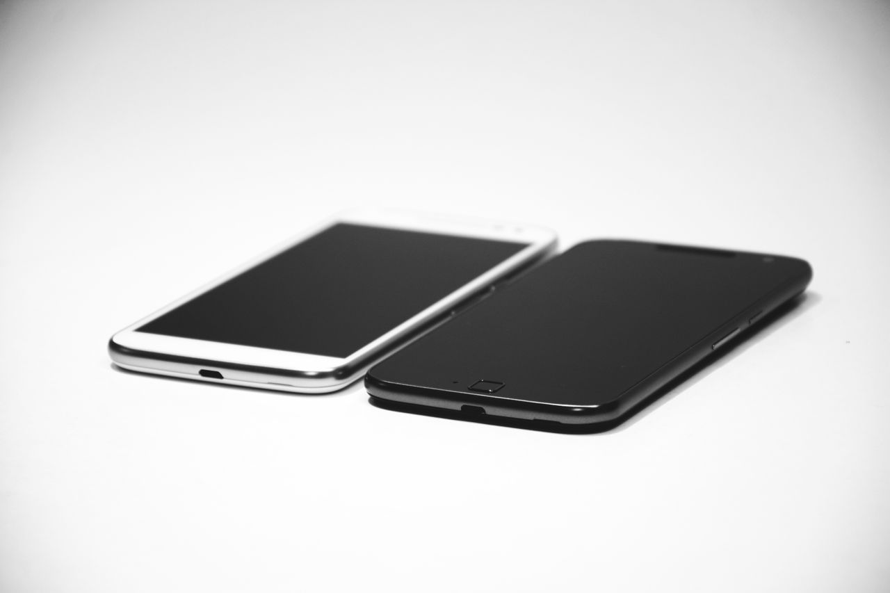 Two smartphones, one black and one white, placed on a white surface, showcasing modern design.